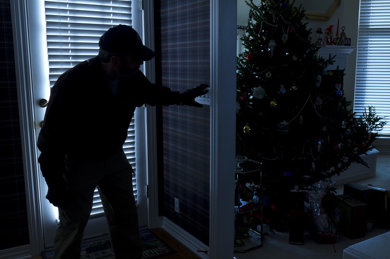 Burglar Breaking In To Home At Christmas Through Back Door