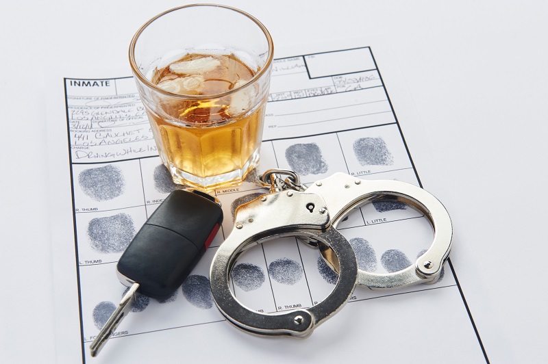 Handcuffs with fingerprints keys and glass of alcohol on ice